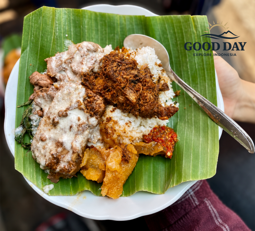 A traditional plate of Gudeg Yogyakarta served on a banana leaf with rice, ayam opor, krecek, sambal, and shredded spicy chicken, showcasing authentic Indonesian cuisine.