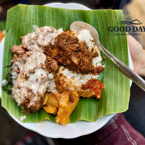 A traditional plate of Gudeg Yogyakarta served on a banana leaf with rice, ayam opor, krecek, sambal, and shredded spicy chicken, showcasing authentic Indonesian cuisine.