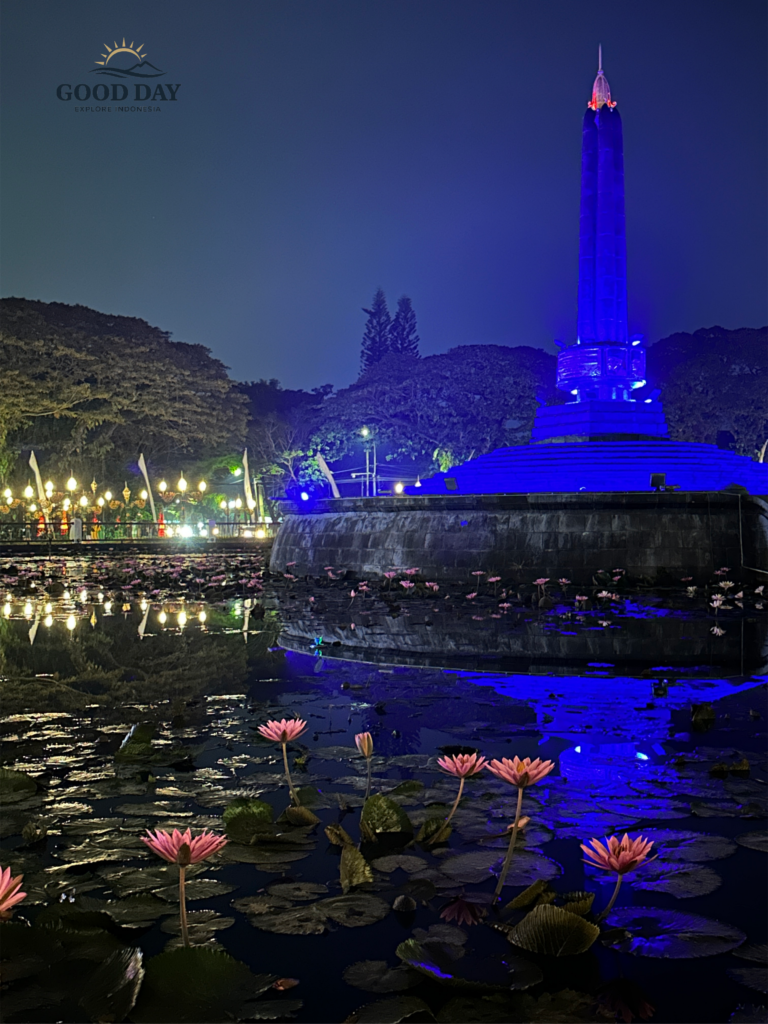Night view of Balai Kota Malang monument surrounded by a lotus pond with blooming pink water lilies and blue illumination reflecting beautifully on the water in Malang, Indonesia.