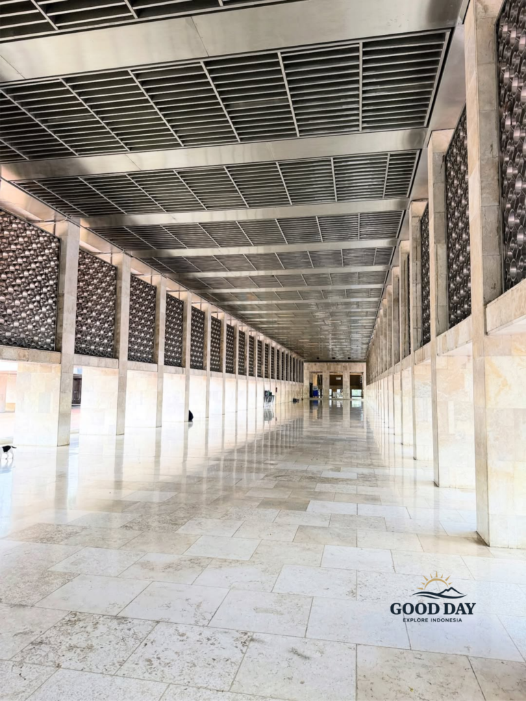 Long marble corridor inside Istiqlal Mosque Jakarta featuring modern Islamic architecture, symmetrical pillars, geometric wall patterns, and spacious prayer hall design in Jakarta, Indonesia.