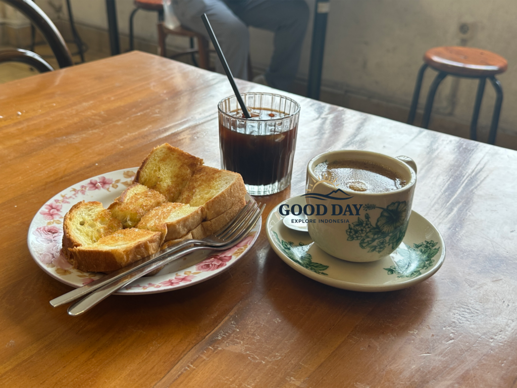 Traditional Indonesian black coffee served with crispy kaya toast on a wooden table inside a vintage café in Glodok Jakarta, creating a cozy old-town coffee shop atmosphere