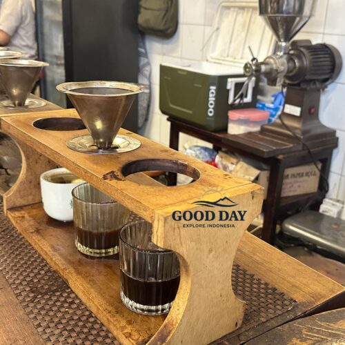 Traditional manual brew coffee setup at a café in Glodok Jakarta featuring metal coffee filters, freshly brewed black coffee, wooden brewing stations, and vintage coffee-making equipment.