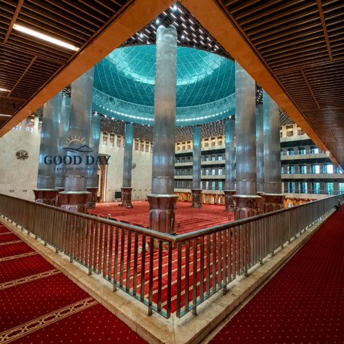 Interior of Istiqlal Mosque Jakarta featuring towering marble columns, a massive central prayer hall, red prayer carpets, and a magnificent domed ceiling. The grand architecture showcases the largest mosque in Southeast Asia and one of Jakarta's most iconic religious landmarks.
