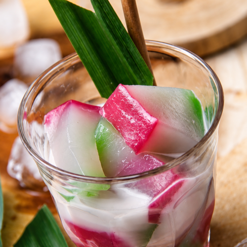 Traditional Selendang Mayang dessert from Jakarta featuring colorful rice flour jelly, creamy coconut milk, and palm sugar syrup served in a glass cup.