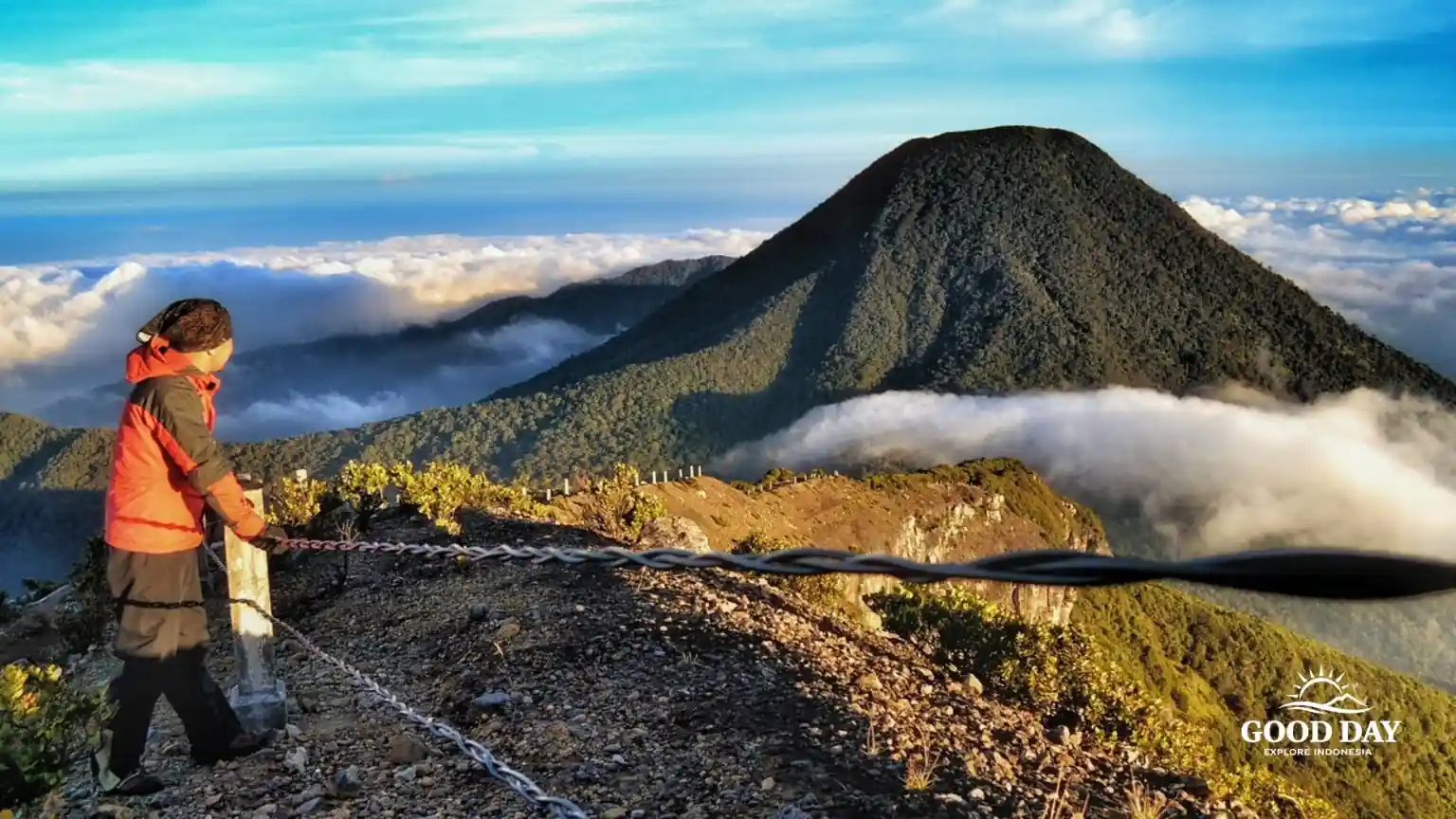 A hiker enjoying the sunrise at Mount Gede in Gunung Gede Pangrango National Park, Bogor, West Java, Indonesia, overlooking a sea of clouds.