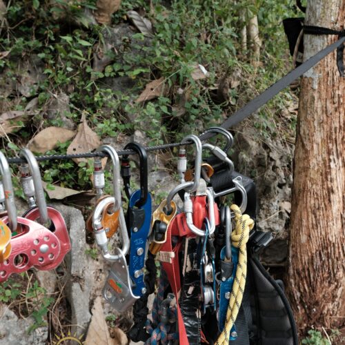 Professional vertical caving equipment prepared at the entrance of Goa Macan Mati in Yogyakarta, Indonesia. Safety gear including ropes, harnesses, descenders, pulleys, and locking carabiners is organized and ready for an underground cave exploration and rope descent adventure in the Gunungkidul karst region.