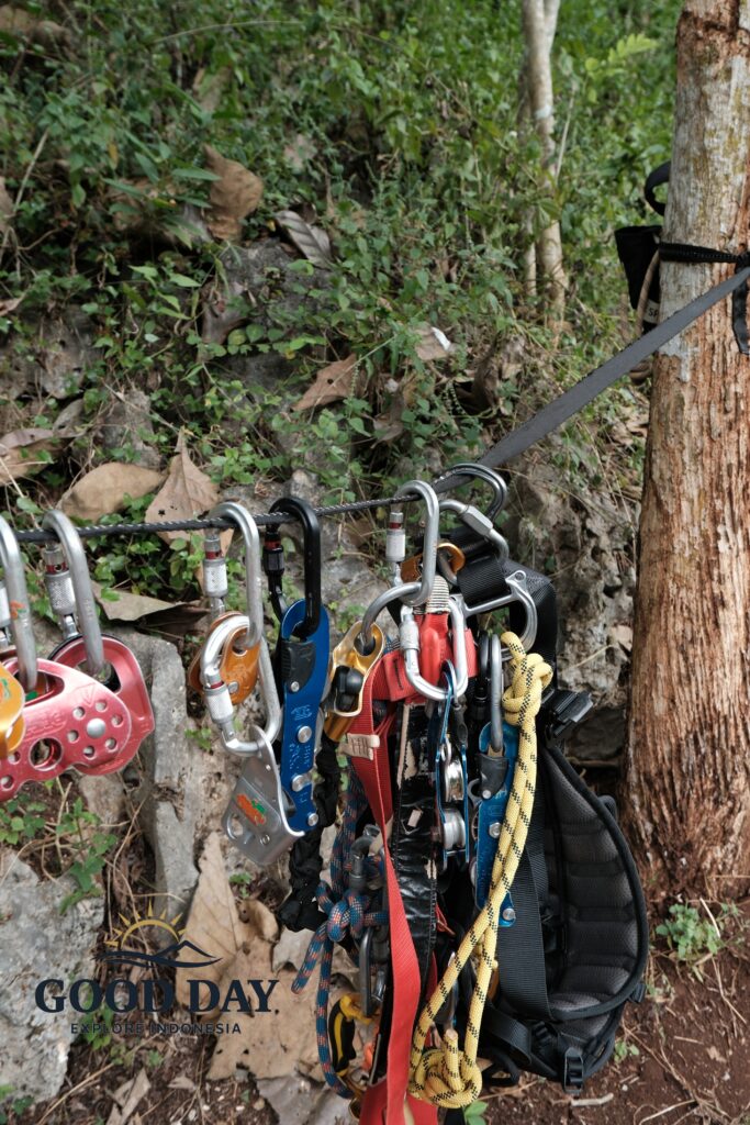 Professional vertical caving equipment prepared at the entrance of Goa Macan Mati in Yogyakarta, Indonesia. Safety gear including ropes, harnesses, descenders, pulleys, and locking carabiners is organized and ready for an underground cave exploration and rope descent adventure in the Gunungkidul karst region.