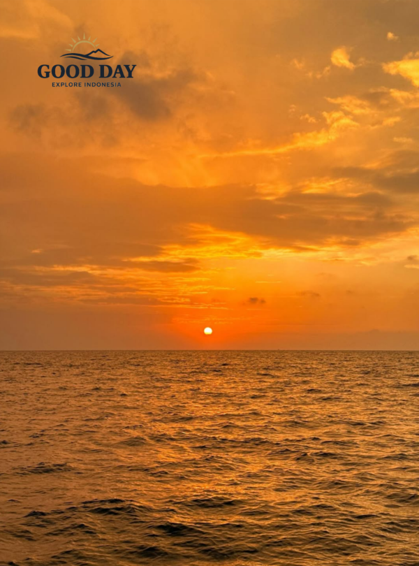 Golden sunset over the calm waters of the Thousand Islands (Pulau Seribu), Indonesia, with the sun resting near the horizon and vibrant orange clouds illuminating the tropical seascape.