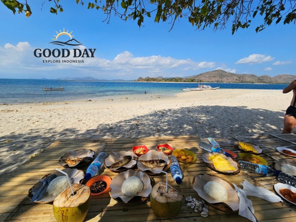 Traditional beachfront lunch served on Gili Nanggu, Lombok, featuring grilled fish, steamed rice, fresh coconut water, tropical fruits, and local Indonesian dishes on a bamboo table overlooking white-sand beaches and crystal-clear turquoise waters.
