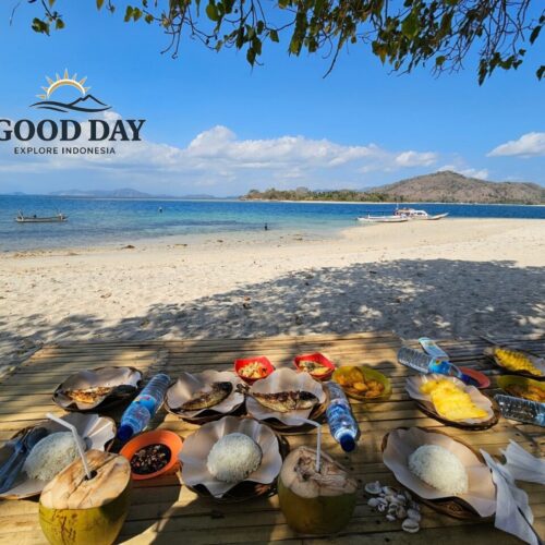 Traditional beachfront lunch served on Gili Nanggu, Lombok, featuring grilled fish, steamed rice, fresh coconut water, tropical fruits, and local Indonesian dishes on a bamboo table overlooking white-sand beaches and crystal-clear turquoise waters.