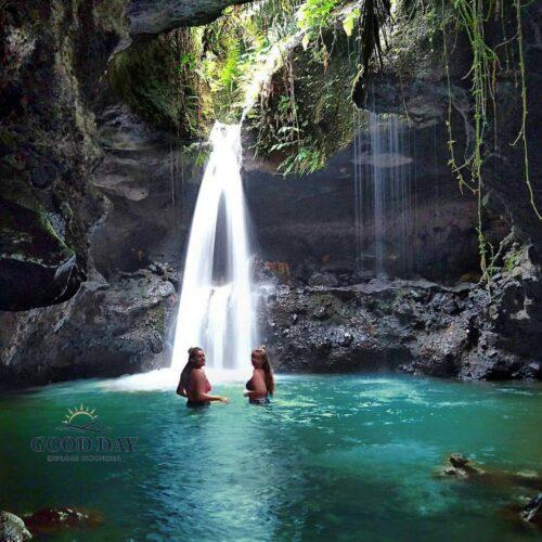 Burung Walet Waterfall in Lombok, Indonesia, featuring a hidden cave-like canyon, crystal-clear turquoise pool, and visitors enjoying a swim beneath a cascading tropical waterfall surrounded by lush jungle vegetation.