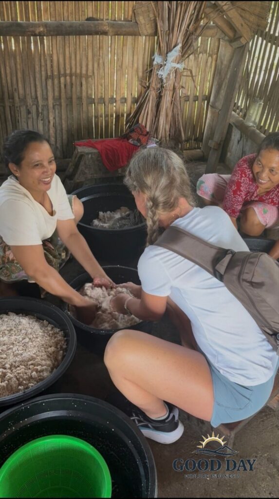Traveler learning how to make traditional coconut oil with local villagers in Lombok, Indonesia. The hands-on cultural experience showcases the traditional process of extracting coconut oil using fresh grated coconut in a rural village setting.