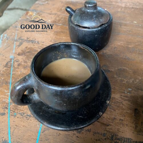 A traditional cup of Lombok coffee served in a handcrafted clay cup on a rustic wooden table. This authentic coffee tasting experience showcases the rich flavors of locally grown Indonesian coffee enjoyed during a cultural village tour in Lombok.