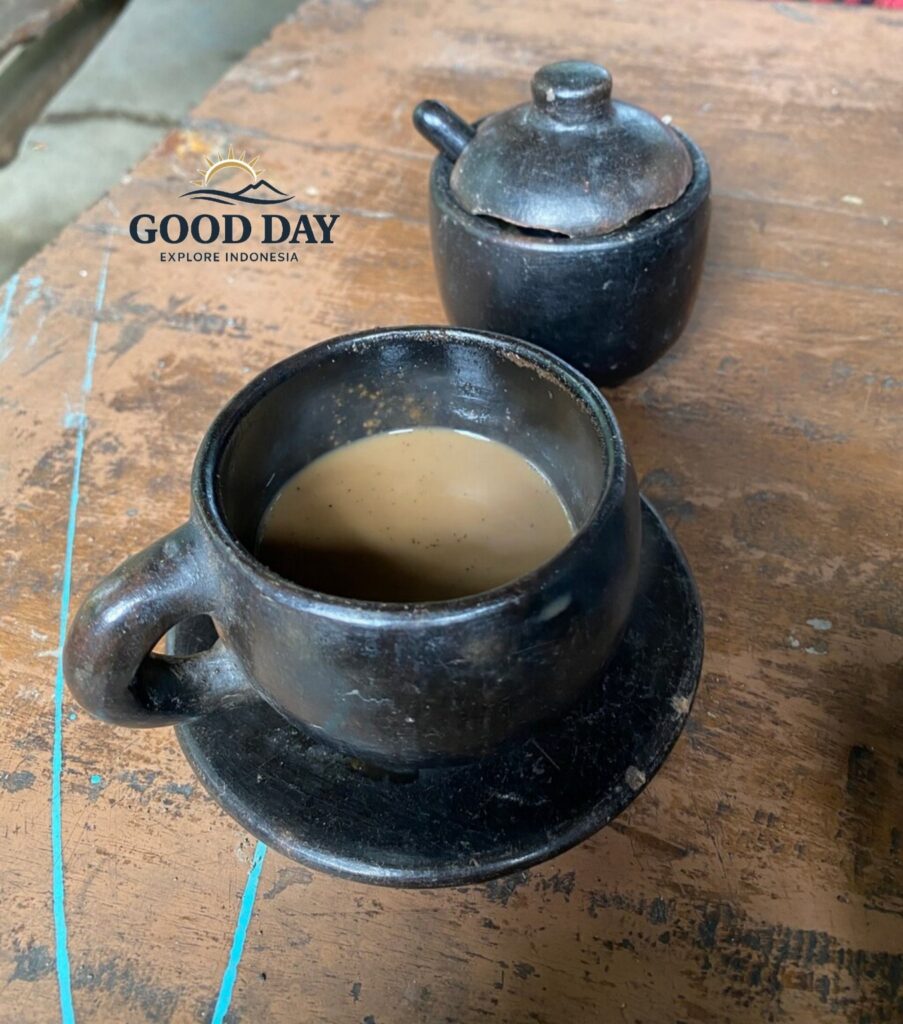A traditional cup of Lombok coffee served in a handcrafted clay cup on a rustic wooden table. This authentic coffee tasting experience showcases the rich flavors of locally grown Indonesian coffee enjoyed during a cultural village tour in Lombok.