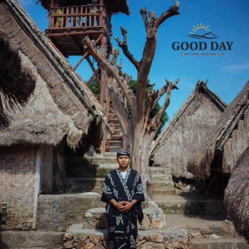 Traditional Sasak villager wearing customary clothing standing among authentic thatched-roof houses at Sade Traditional Village in Lombok, Indonesia, showcasing the rich cultural heritage and traditional architecture of the Sasak people.