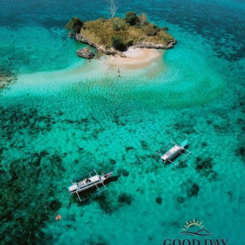 A breathtaking aerial view of Gili Petelu, Lombok, featuring a small tropical island surrounded by crystal-clear turquoise waters, vibrant coral reefs, and traditional boats anchored nearby. This hidden paradise is one of the best snorkeling and island-hopping destinations in East Lombok, Indonesia.