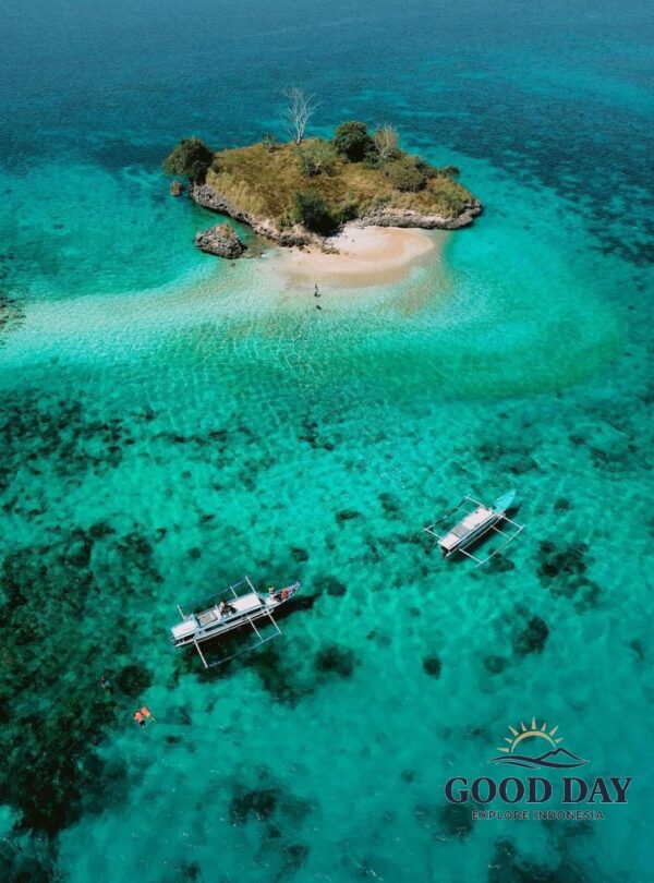A breathtaking aerial view of Gili Petelu, Lombok, featuring a small tropical island surrounded by crystal-clear turquoise waters, vibrant coral reefs, and traditional boats anchored nearby. This hidden paradise is one of the best snorkeling and island-hopping destinations in East Lombok, Indonesia.