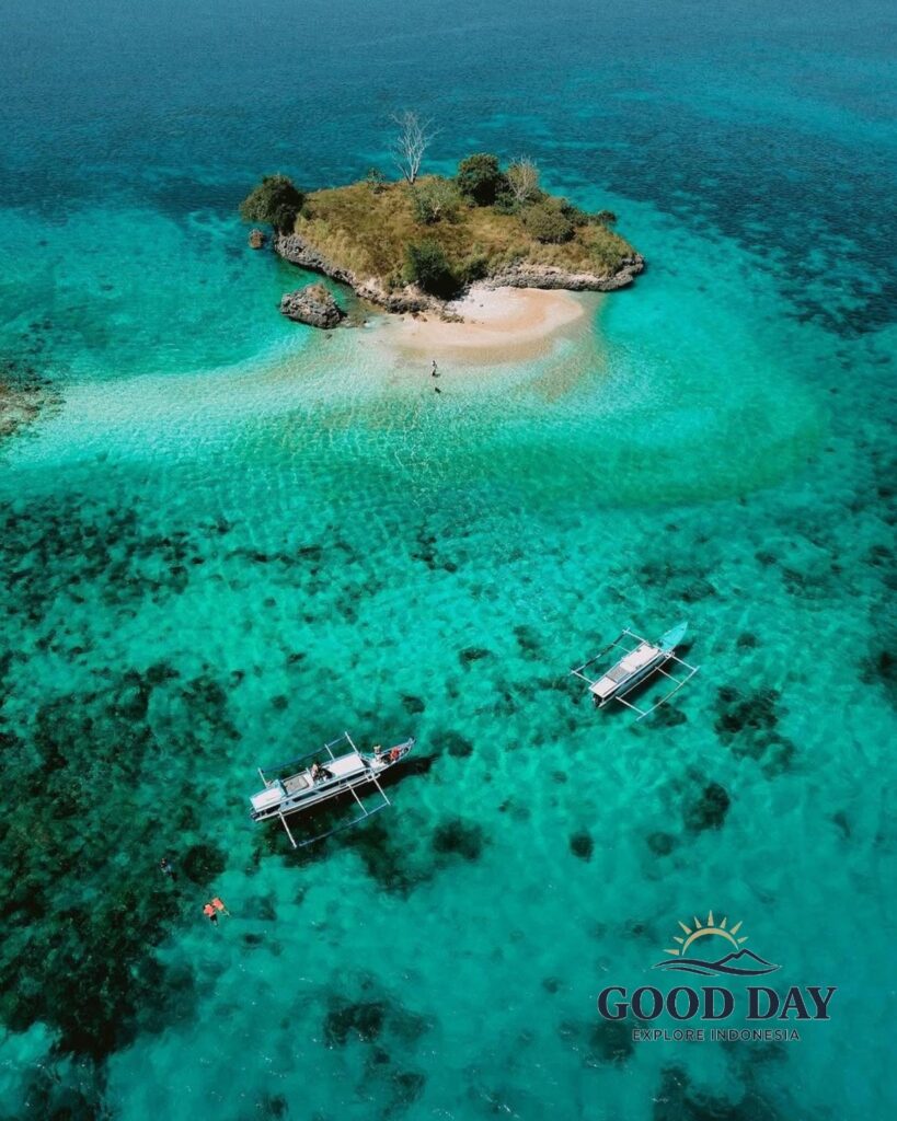 A breathtaking aerial view of Gili Petelu, Lombok, featuring a small tropical island surrounded by crystal-clear turquoise waters, vibrant coral reefs, and traditional boats anchored nearby. This hidden paradise is one of the best snorkeling and island-hopping destinations in East Lombok, Indonesia.
