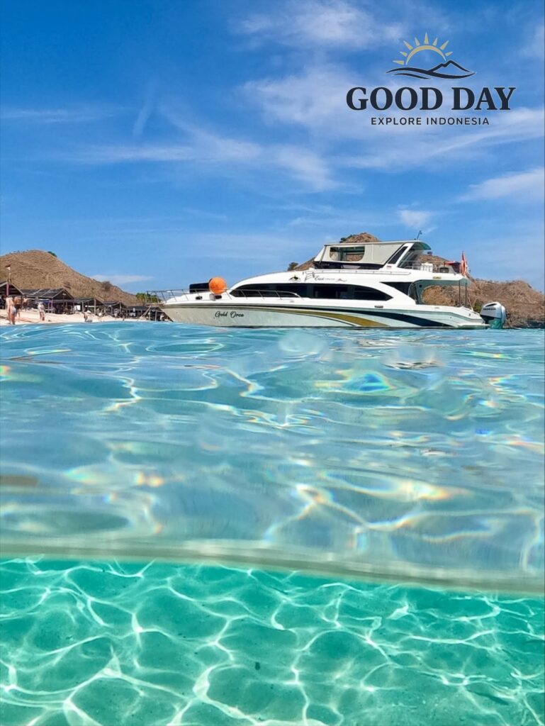 Luxury yacht anchored in the crystal-clear turquoise waters of Lombok, Indonesia, with stunning coastal hills and a tropical island backdrop. The transparent sea and vibrant blue sky create a picture-perfect paradise for island hopping, snorkeling, and luxury marine adventures.