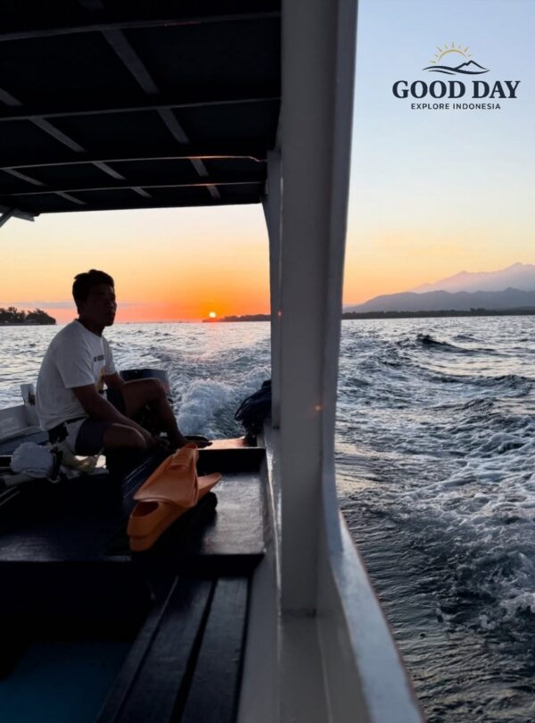 Traditional boat ride at sunset in Lombok, Indonesia, with golden sunlight reflecting on the ocean and views of Mount Rinjani in the distance, creating a peaceful island travel experience.