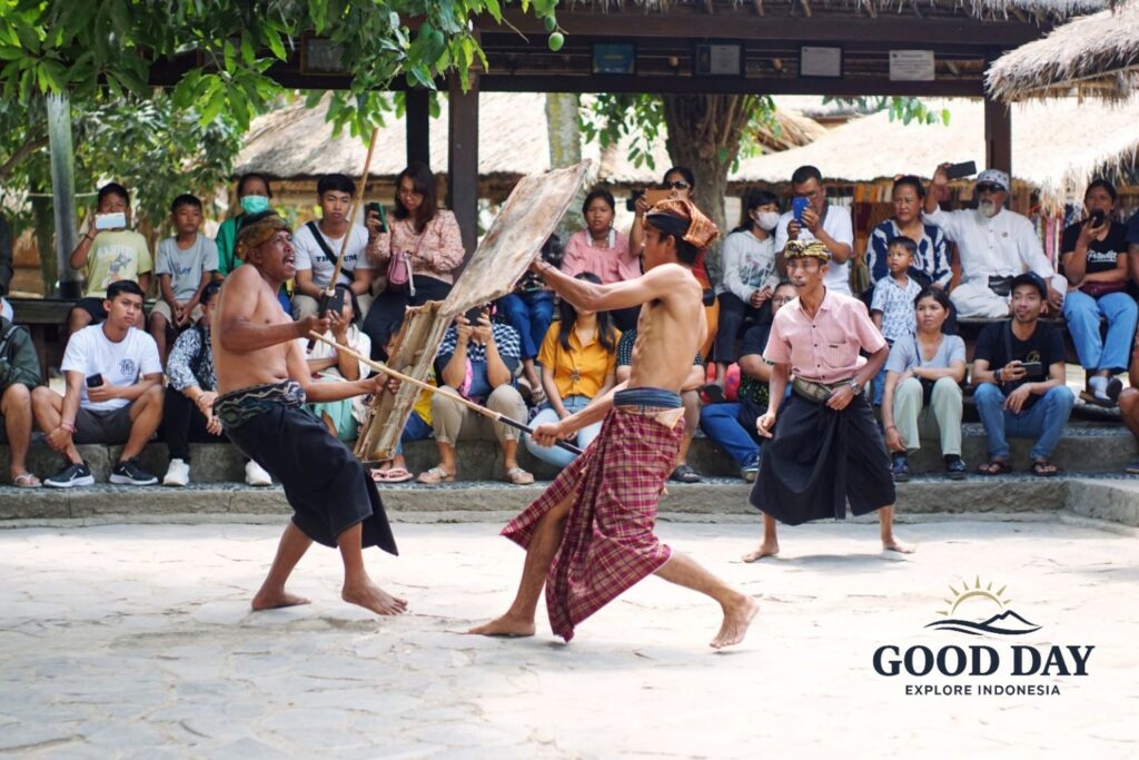 Traditional Peresean stick-fighting performance in Sade Traditional Village, Lombok, Indonesia. Sasak warriors wearing traditional sarongs engage in a cultural martial arts demonstration while visitors watch and learn about Lombok’s rich indigenous heritage.