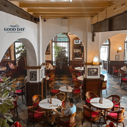 Interior of Café Batavia Jakarta featuring elegant colonial architecture, marble-top tables, vintage wooden furniture, red-upholstered chairs, and arched hallways. Guests relax and dine within one of the most iconic heritage cafés overlooking Kota Tua Jakarta.