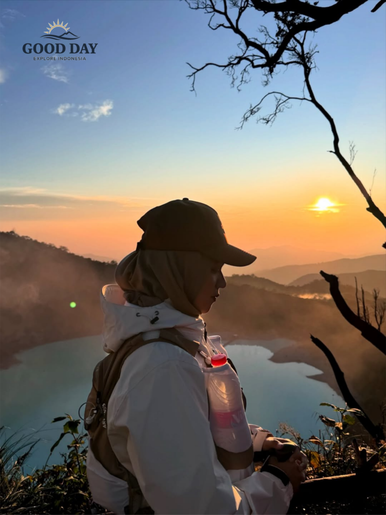 Traveler enjoying sunrise at Sunan Ibu Viewpoint overlooking the turquoise crater lake of Kawah Putih in Ciwidey, Bandung, West Java, Indonesia.
