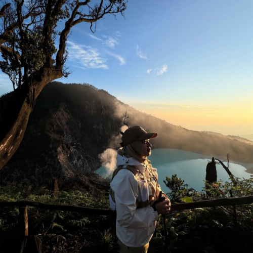 Traveler enjoying a golden sunrise at Sunan Ibu Viewpoint overlooking the turquoise volcanic crater lake of Kawah Putih in Ciwidey, Bandung, West Java, Indonesia.
