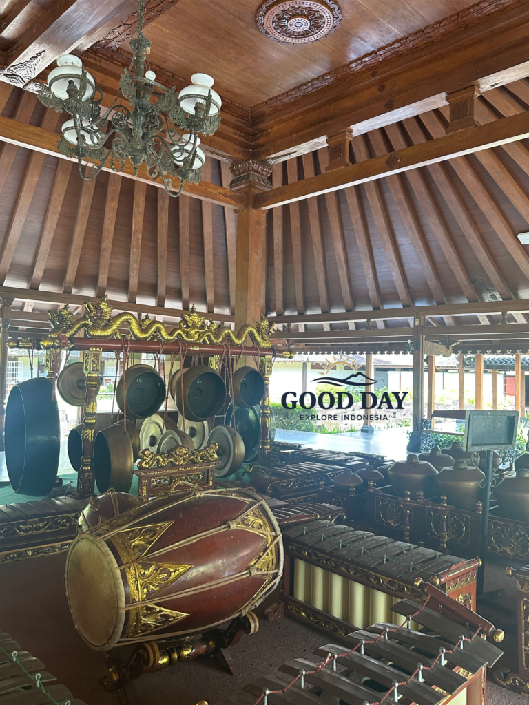 Traditional Javanese gamelan orchestra set inside a historic wooden pendopo in Yogyakarta, Indonesia. The ensemble features bronze gongs, metallophones, kendang drums, and intricately carved wooden decorations beneath a classic Joglo-style roof, showcasing the rich cultural heritage of Java.