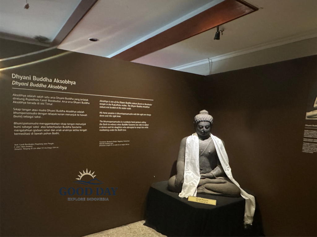 Dhyani Buddha Akshobhya statue displayed inside the Borobudur Museum in Yogyakarta, Indonesia. The ancient Buddhist sculpture is showcased in an exhibition space with informative panels explaining its historical, spiritual, and cultural significance within Borobudur Temple.