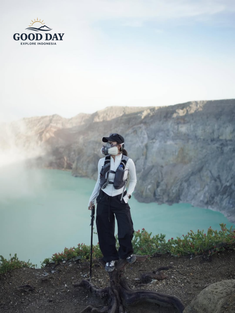 A traveler wearing a gas mask standing on the rim of Kawah Ijen Crater in East Java, Indonesia, overlooking the stunning turquoise acidic lake and dramatic volcanic landscape.