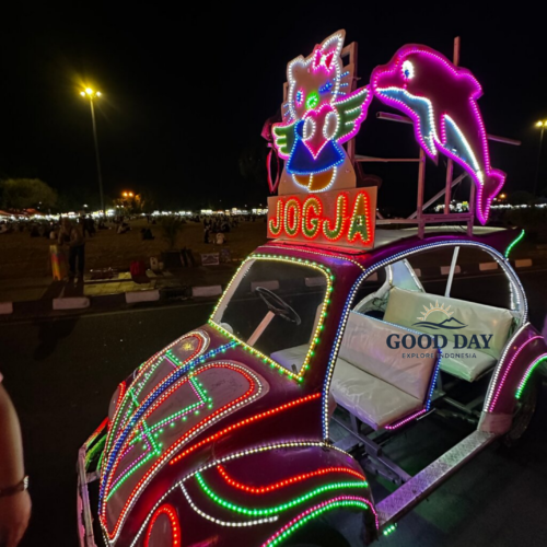 Colorful illuminated becak car at Alun-Alun Kidul Yogyakarta, Indonesia, decorated with vibrant LED lights and popular cartoon-themed ornaments during a lively evening atmosphere.