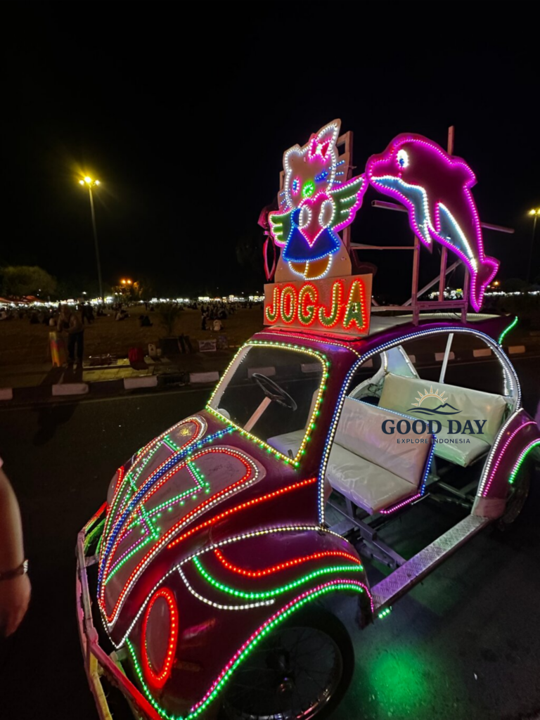 Colorful illuminated becak car at Alun-Alun Kidul Yogyakarta, Indonesia, decorated with vibrant LED lights and popular cartoon-themed ornaments during a lively evening atmosphere.