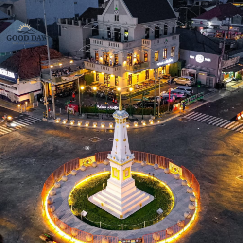 Aerial view of Tugu Yogyakarta at night, featuring the iconic white monument illuminated by golden lights at the center of one of Yogyakarta's most famous landmarks.
