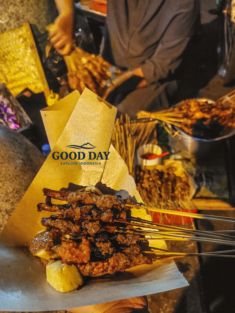 Traditional satay skewers being freshly grilled and served at a street food stall in Malioboro, Yogyakarta, Indonesia, showcasing one of the city's most popular night market culinary experiences.