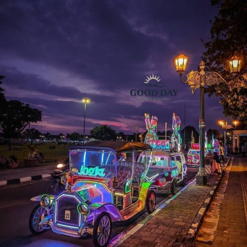 A colorful neon-lit unicorn-themed pedicab (becak hias) carrying visitors along a street in Yogyakarta, Indonesia, during a stunning purple and orange sunset, showcasing the vibrant evening atmosphere of Jogja.