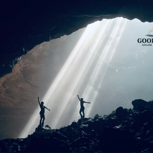 Visitors standing beneath the famous Heaven's Light sunbeams inside Jomblang Cave, Yogyakarta, Indonesia, as sunlight streams through the cave opening and illuminates the vast underground chamber.