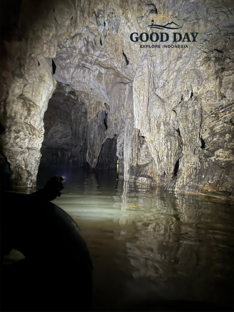 Ancient limestone formations and underground river passage inside Jomblang Cave, Yogyakarta, Indonesia, featuring stunning stalactites, reflective water, and a hidden cave exploration route.