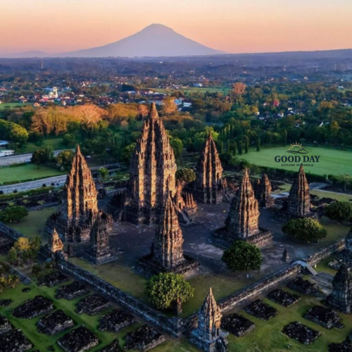 Aerial view of Prambanan Temple in Yogyakarta, Indonesia, featuring the towering Hindu temple complex with Mount Merapi rising in the background during sunrise.
