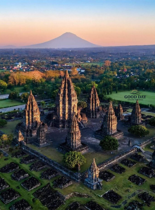 Aerial view of Prambanan Temple in Yogyakarta, Indonesia, featuring the towering Hindu temple complex with Mount Merapi rising in the background during sunrise.