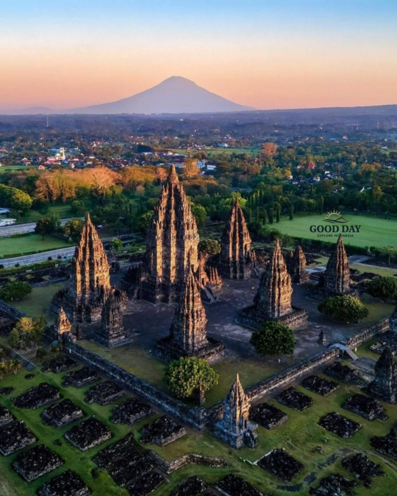 Aerial view of Prambanan Temple in Yogyakarta, Indonesia, featuring the towering Hindu temple complex with Mount Merapi rising in the background during sunrise.