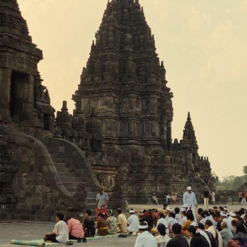 Visitors participating in a cultural and religious gathering at Prambanan Temple in Yogyakarta, Indonesia, with the majestic ancient Hindu temple rising in the background.