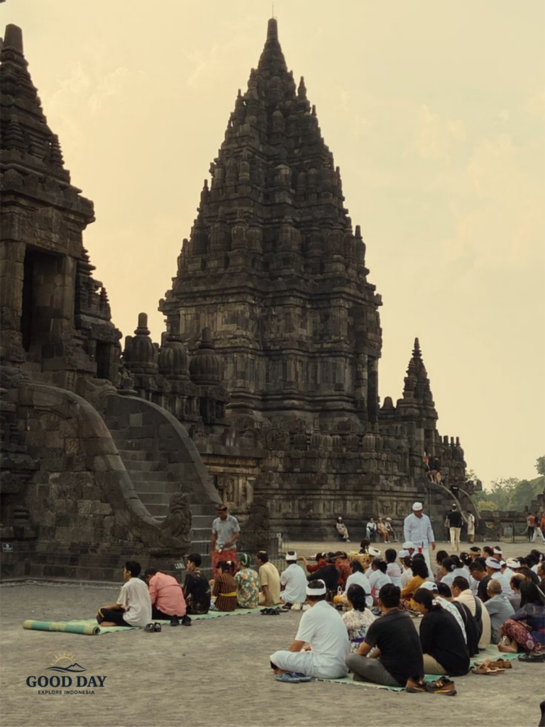 Visitors participating in a cultural and religious gathering at Prambanan Temple in Yogyakarta, Indonesia, with the majestic ancient Hindu temple rising in the background.