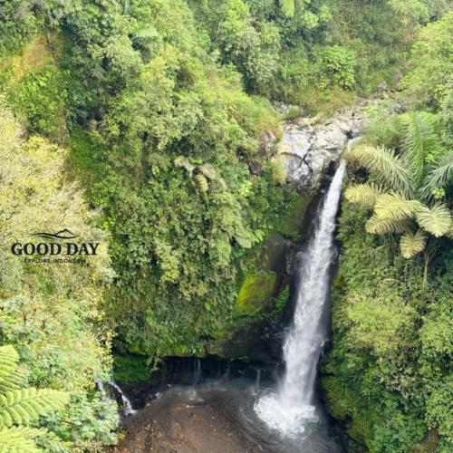 Kedung Kayang Waterfall in Yogyakarta, Indonesia, surrounded by lush tropical rainforest and steep green cliffs. The waterfall cascades into a rocky pool below, creating a scenic natural landscape in the foothills of Mount Merapi near Magelang and Yogyakarta.