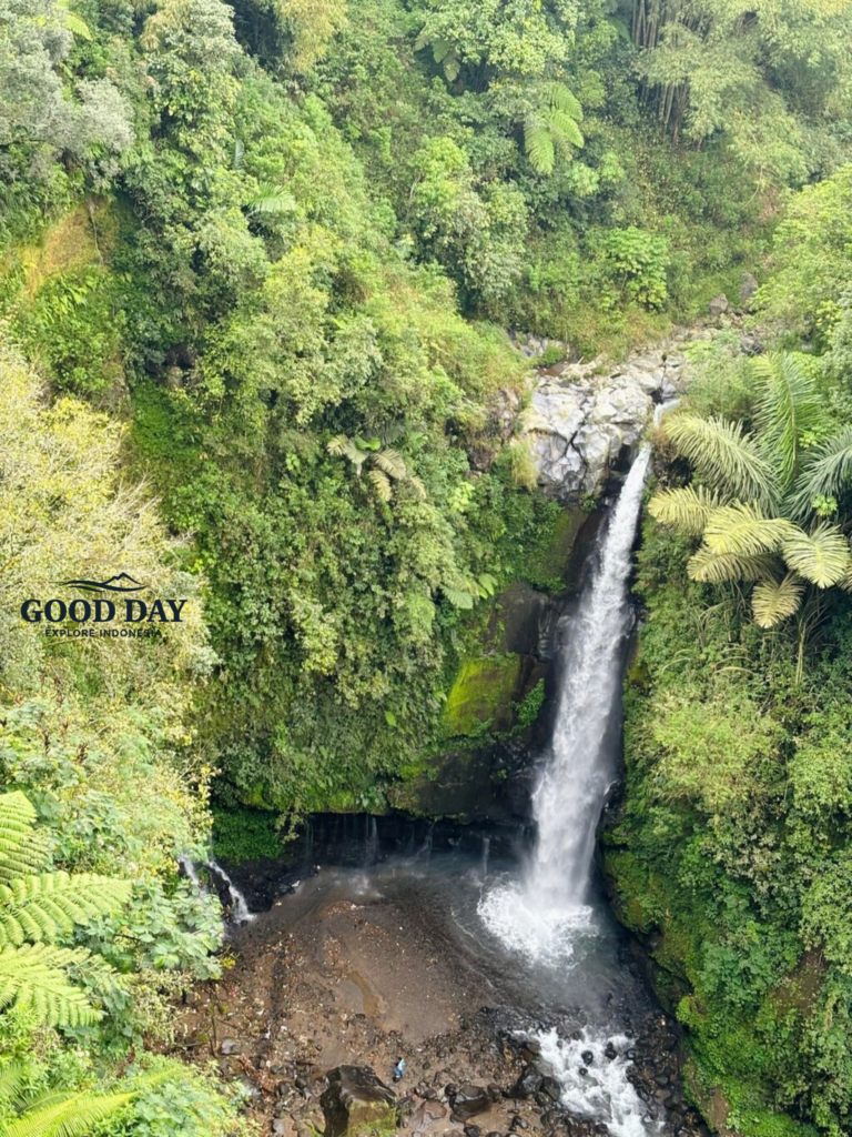 Kedung Kayang Waterfall in Yogyakarta, Indonesia, surrounded by lush tropical rainforest and steep green cliffs. The waterfall cascades into a rocky pool below, creating a scenic natural landscape in the foothills of Mount Merapi near Magelang and Yogyakarta.