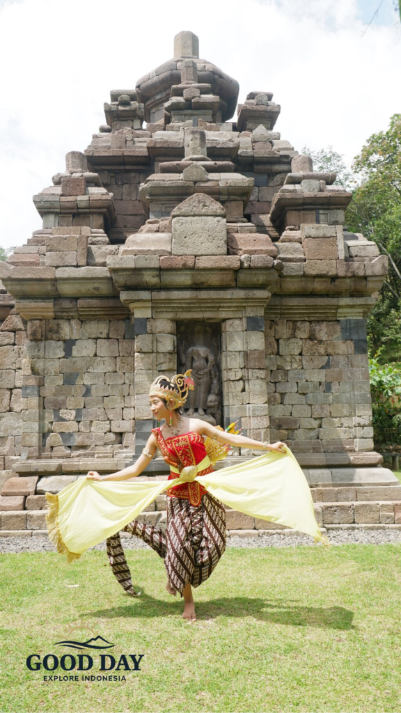 Traditional Javanese dancer performing a cultural dance in front of Selogriyo Temple, Yogyakarta, wearing colorful traditional attire with a historic ancient Hindu temple as the backdrop.