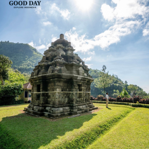 Ancient Selogriyo Temple standing amidst lush green hills under a bright blue sky in Magelang near Yogyakarta, showcasing classic Hindu temple architecture surrounded by peaceful natural landscapes.