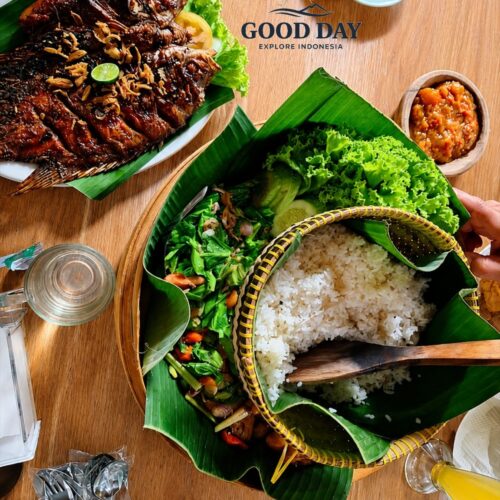 Traditional Sundanese food from Bandung served on banana leaves, featuring grilled fish, steamed rice in a woven basket, fresh vegetables, sambal, and local side dishes on a wooden dining table.