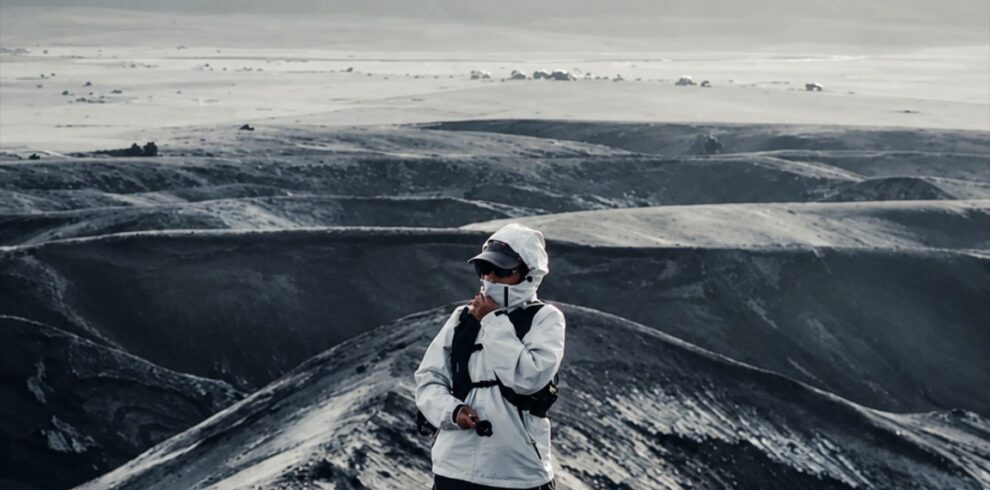 Traveler standing on the dramatic volcanic landscape of Mount Bromo, surrounded by black sand hills and rugged terrain in Bromo Tengger Semeru National Park, East Java, Indonesia.