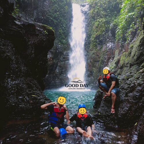Visitors posing beside the stunning Curug Naga waterfall in Bogor, West Java, surrounded by towering canyon walls, crystal-clear water, and lush tropical rainforest during a body rafting adventure.